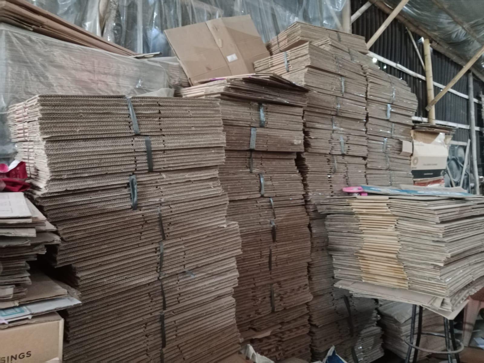 Tumpukan kardus bekas tersusun rapi dan terikat di gudang